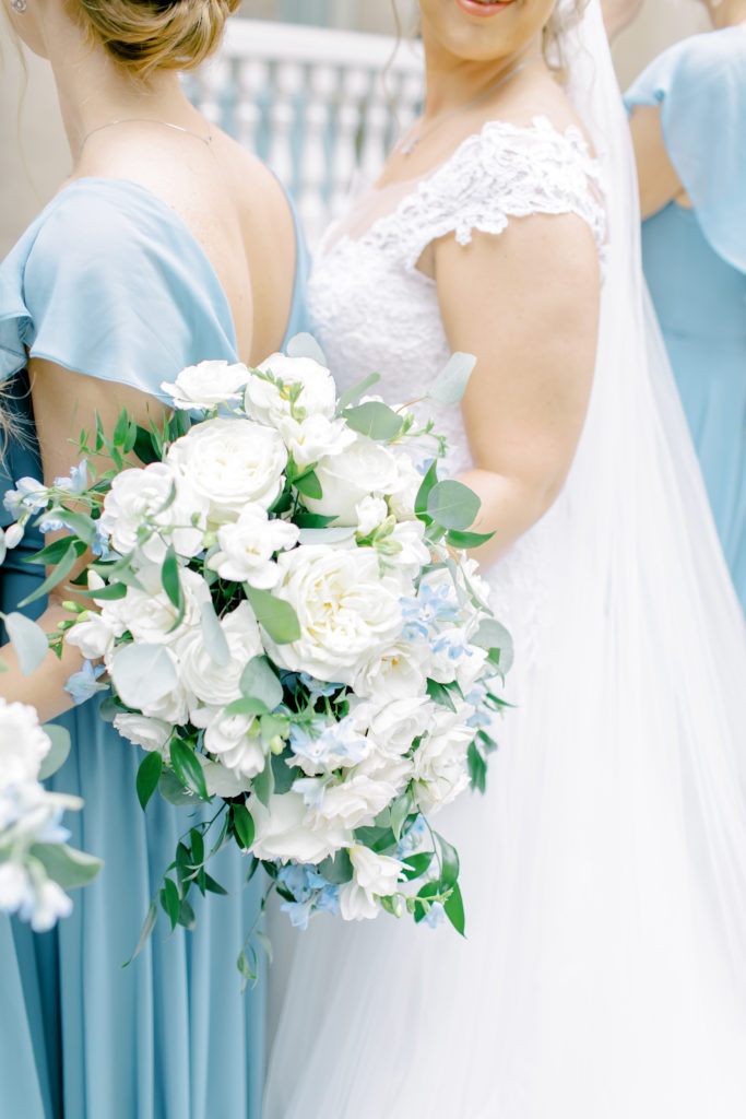 bride's beautiful white and green flowers next to her bridesmaids in blue