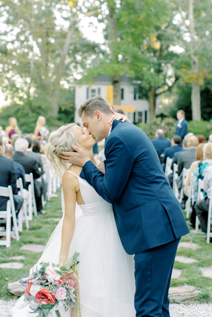 husband and wife kiss at the end of the aisle