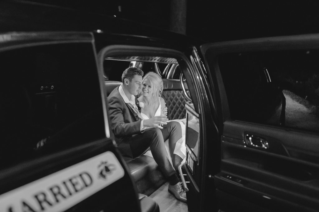 bride and groom leaving their wedding in a limo