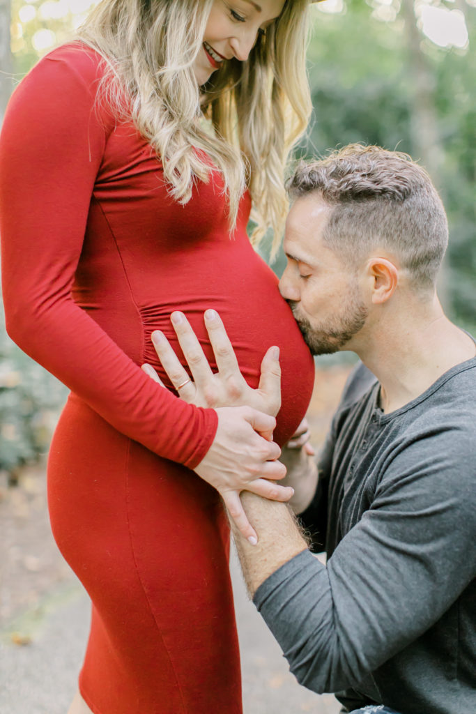 husband kisses wife's belly during maternity session photo