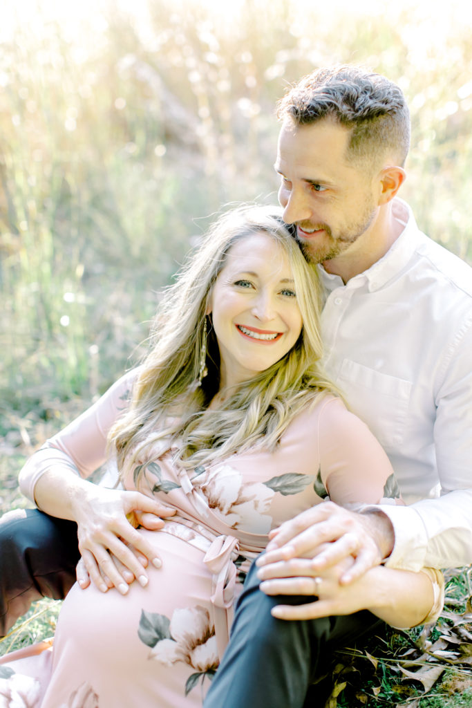 maternity session photo of couple laughing in field