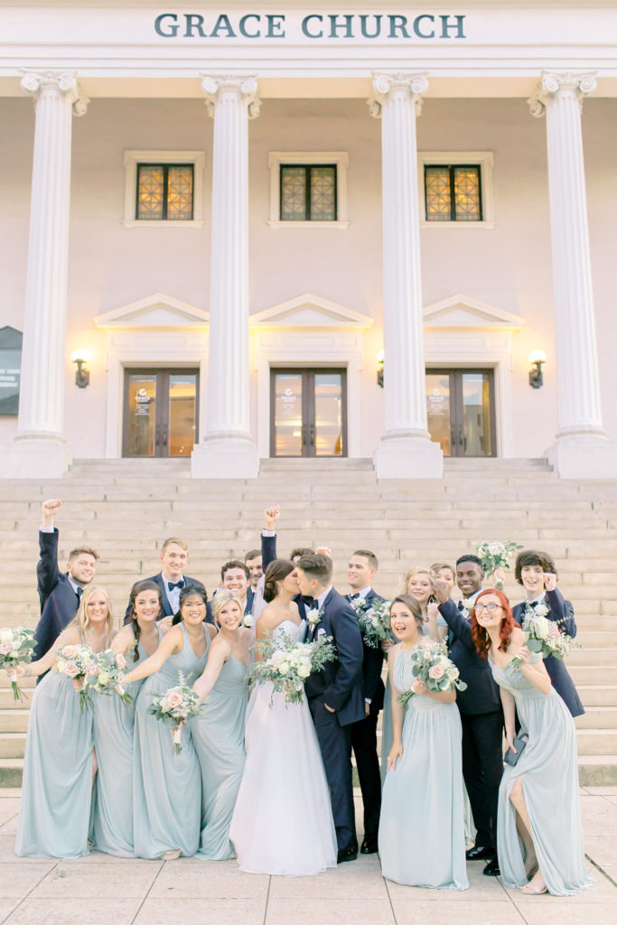 bride and groom kiss while bridal party cheer