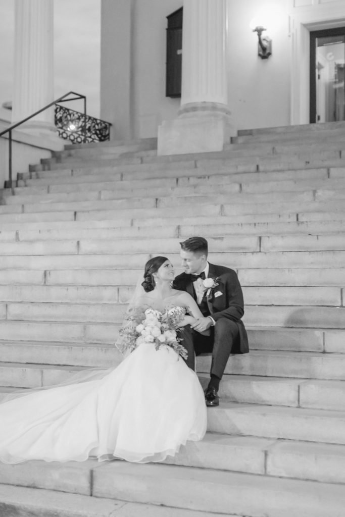 bride and groom sit on the steps of their church
