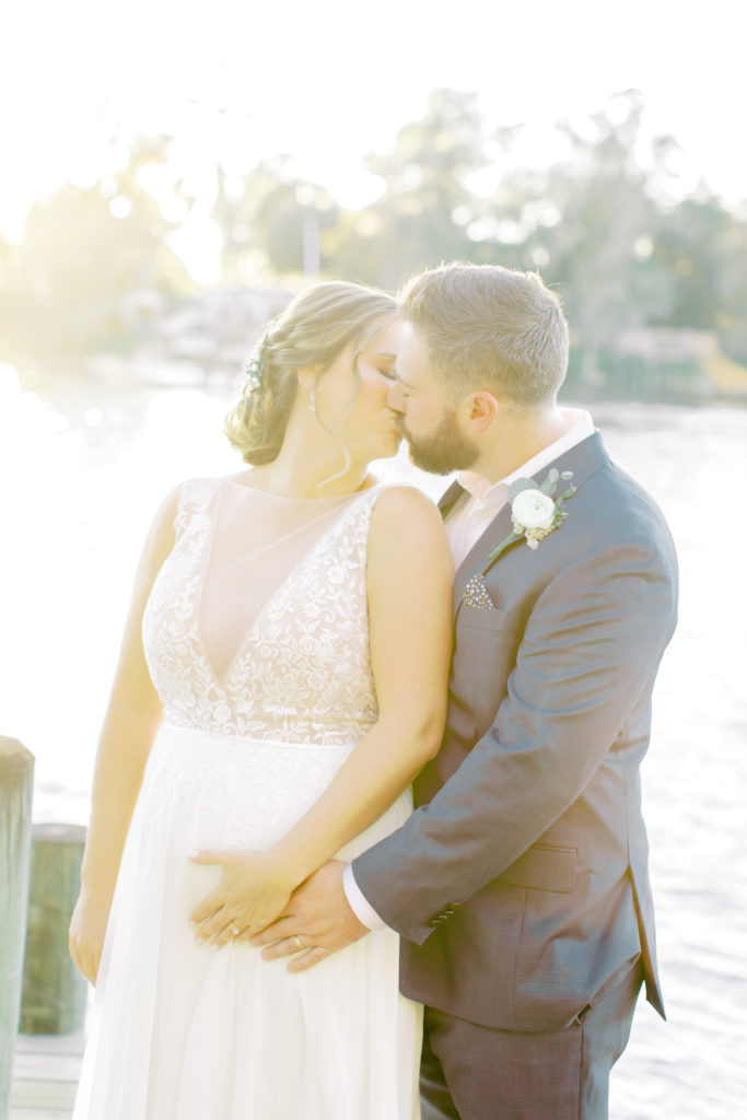 Bride and groom kissing on a dock in Flemming Island, groom holding her baby belly | Jacksonville, Wedding Photographer | Photo by Mary Catherine Echols