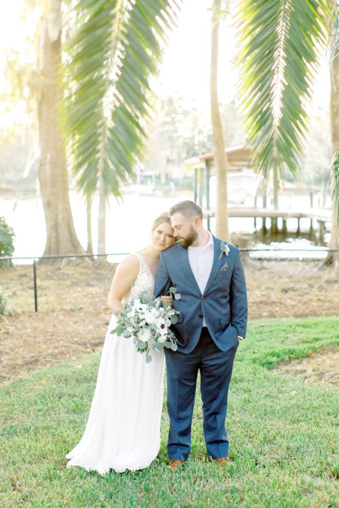 Beautiful shot of bride hugging up on the back of the groom with palm tree branches hanging over them | Jacksonville, Wedding Photographer | Photo by Mary Catherine Echols