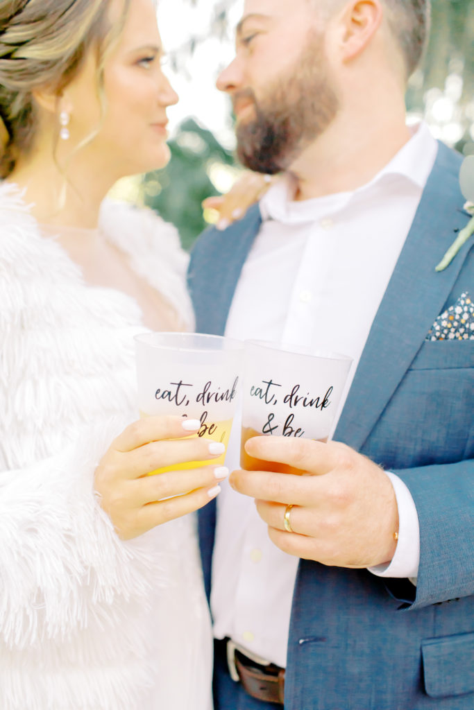 bride and groom clink their drink cups at the reception and look at each other | Jacksonville Wedding Photographer | Photo by Mary Catherine Echols