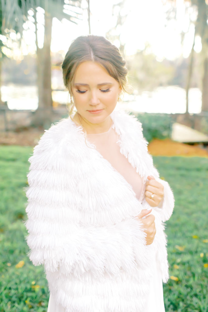 close up shot of the bride looking down with her fluffy reception white coat on | Jacksonville Wedding Photographer | Photo by Mary Catherine Echols