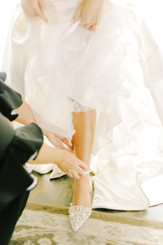 mom helping bride get into her shoes | Photo by Mary Catherine Echols