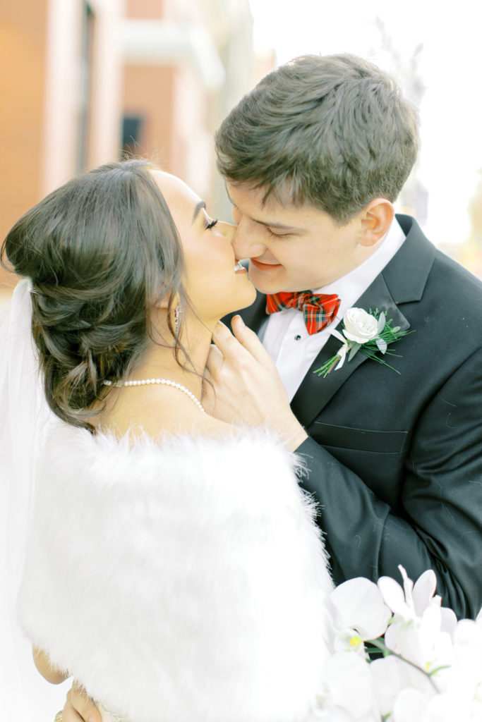 groom kisses bride who is wearing her fur shawl | Photo by Mary Catherine Echols