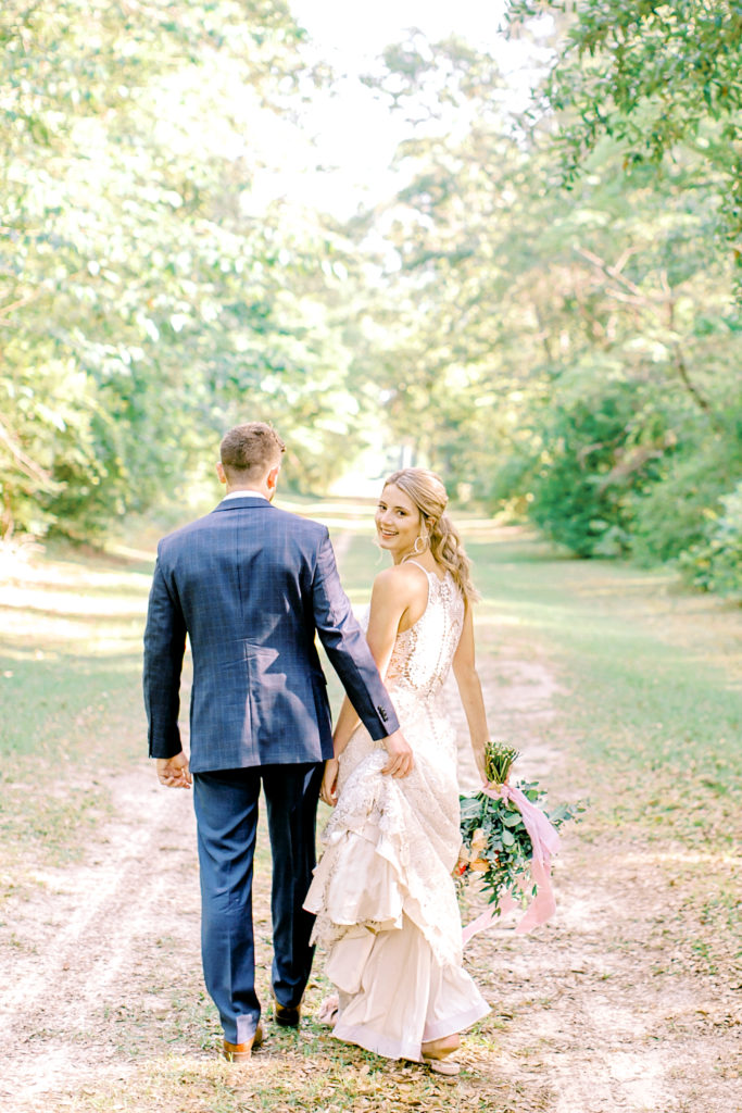 bride and groom walking away, bride smiling at camera
