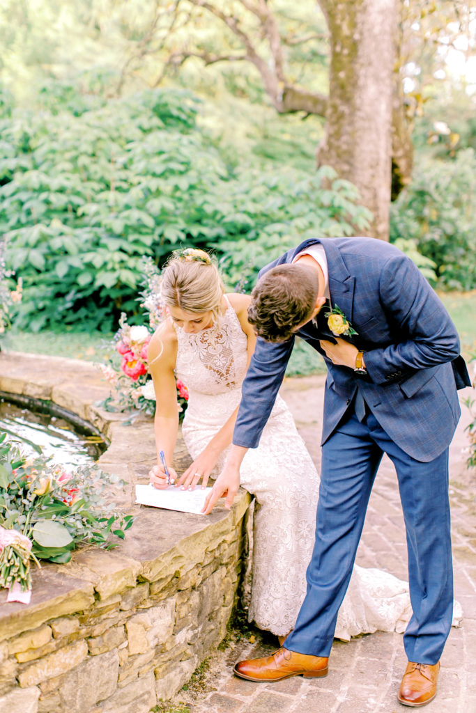 bride and groom sign their marriage license by the fountain at wavering place | photo by mary catherine echols