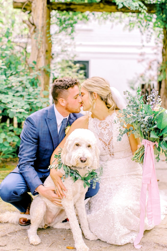 wavering place elopement, bride and groom kiss under arch with their golden doodle | photo by mary catherine echols