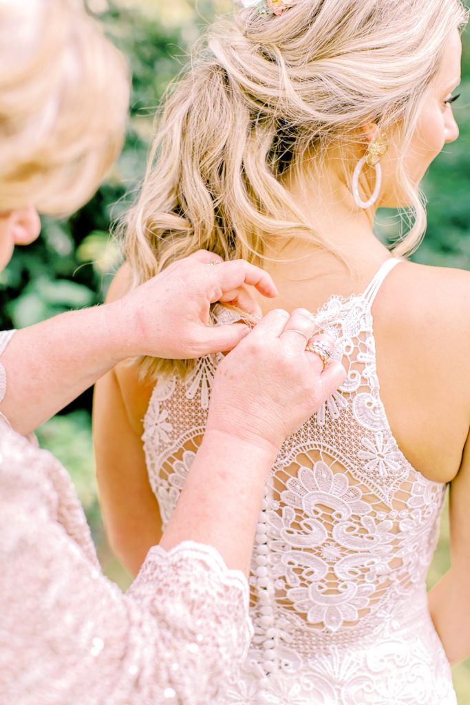 mom helping bride into dress, close up shot of the back | photo by mary catherine echols