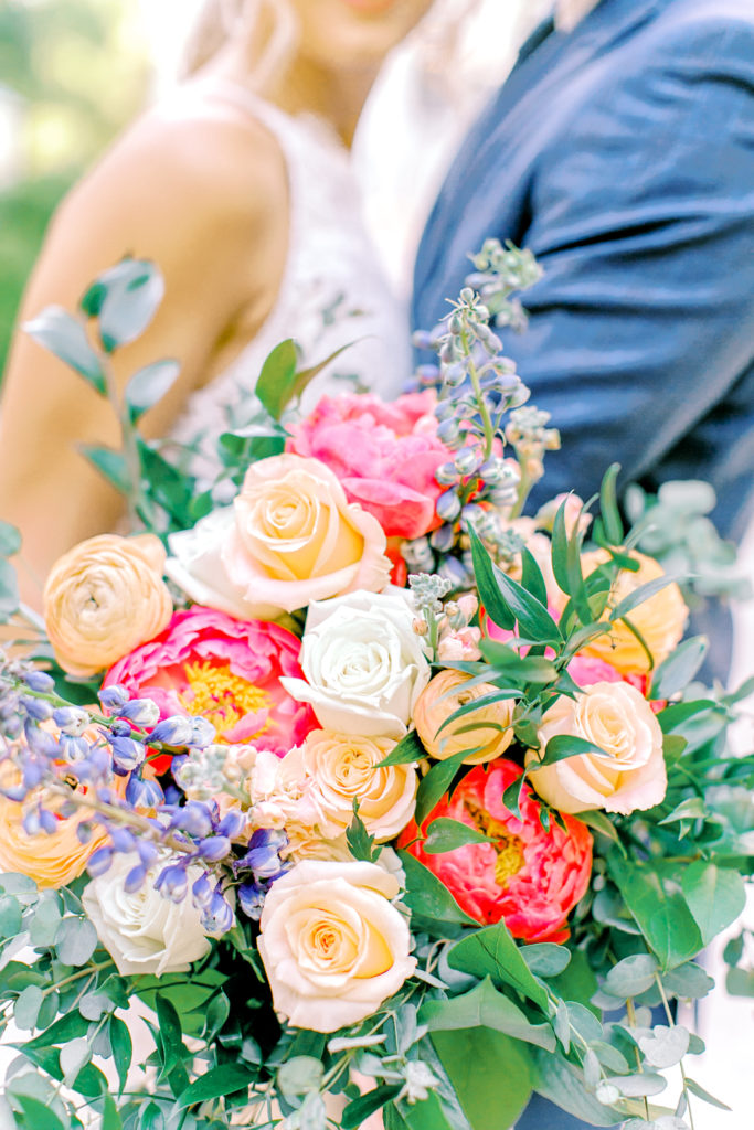 colorful wedding bouquet, bride and groom looking at eachother | photo by mary catherine echols