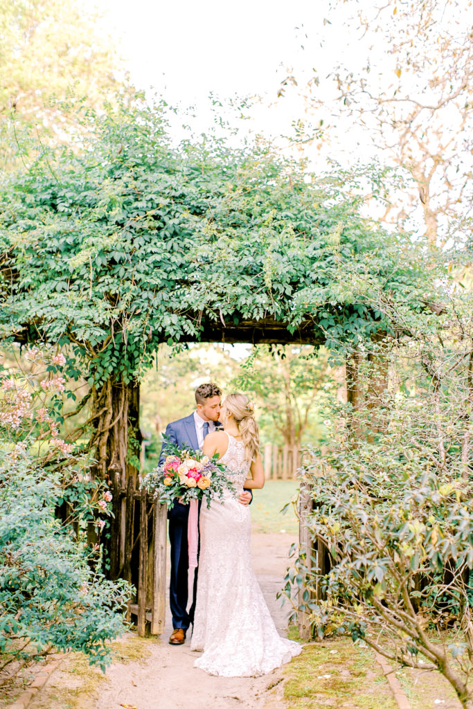 bride and groom kiss under arch at wavering place in south carolina | photo by mary catherine echols