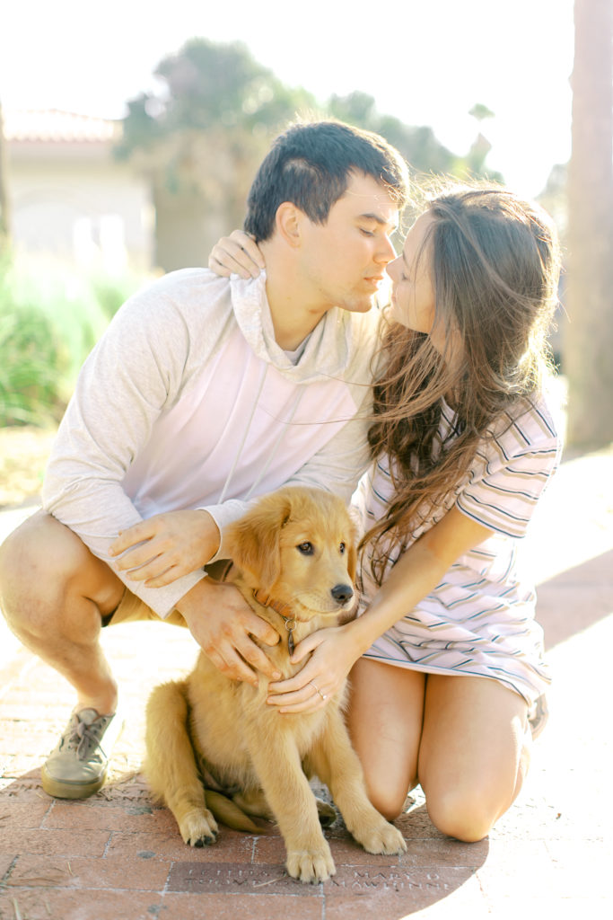 couple kisses knelling down with their pupppy in jacksonville
