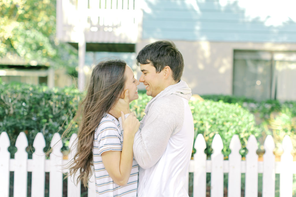 engaged couple looks at each other in front of a blue beach house in jacksonville