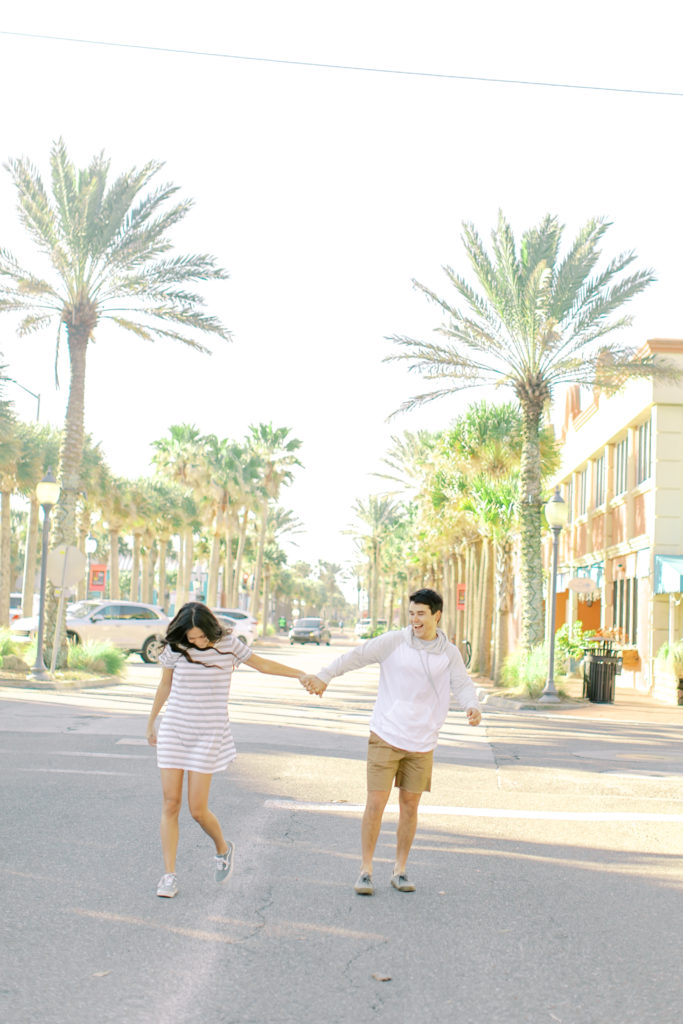 engaged couple running and holding hands in atlantic beach