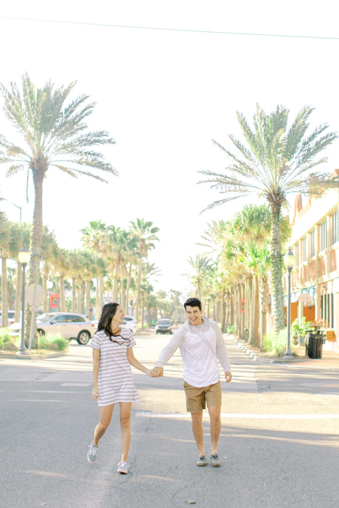 engaged couple running down the road on atlantic beach